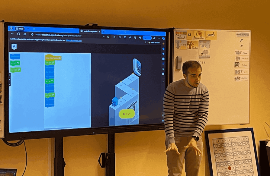 Elias unterrichtet Kinder in visueller Programmierung am interaktiven Bildschirm